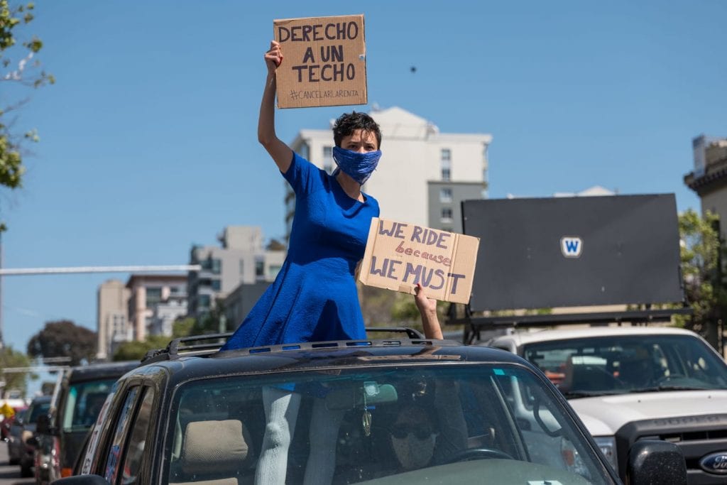 a person hold a #cancelrent sign in spanish.