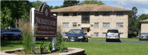 the outside of a residential property in Minnesota, which was preserved using the NOAH Impact Fund. A sign and a few cars can be seen in front of the building.