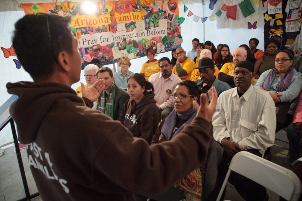 Man speaks in front of a crowd at a community meeting