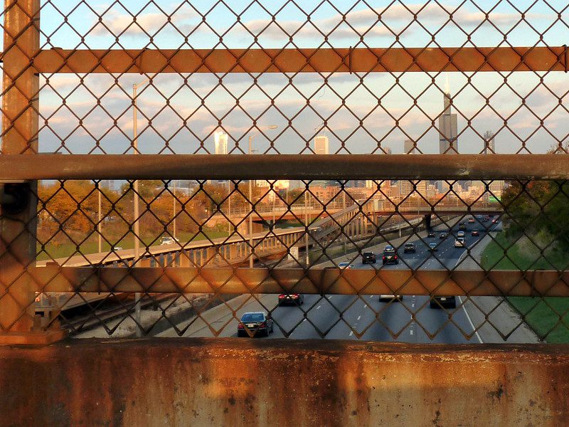 A view of the Chicago skyline through a rusty chain-link fence