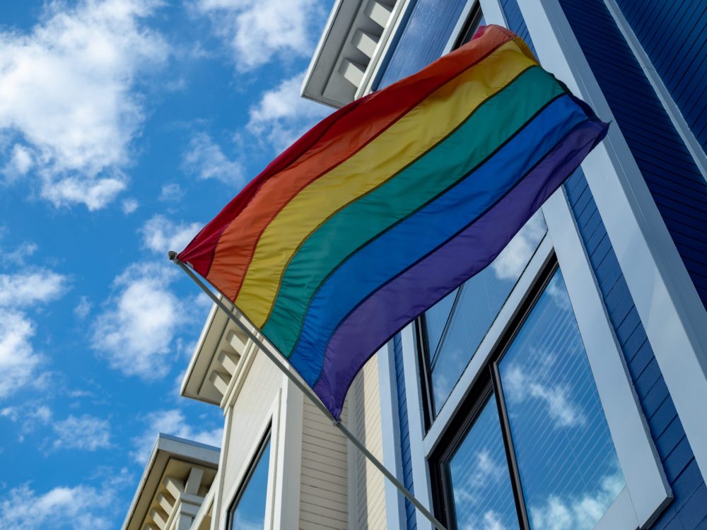 A rainbow flag waves outside of a window