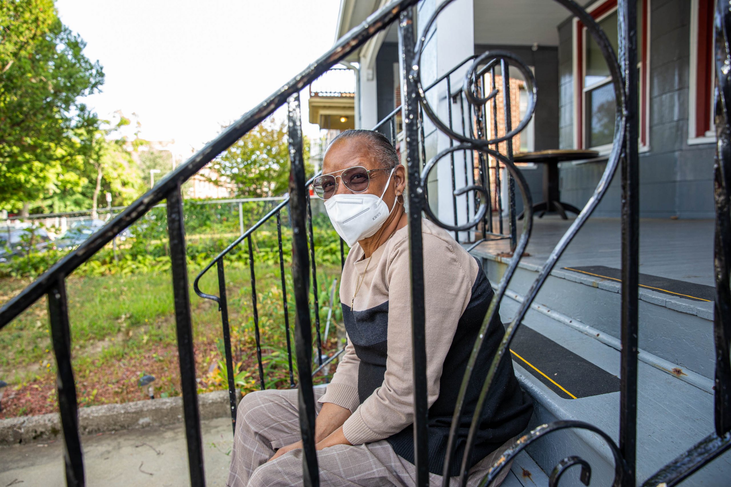 A person sits outside on the steps of their home. They were able to stay there because they received eviction diversion funds, or RAFT funding.