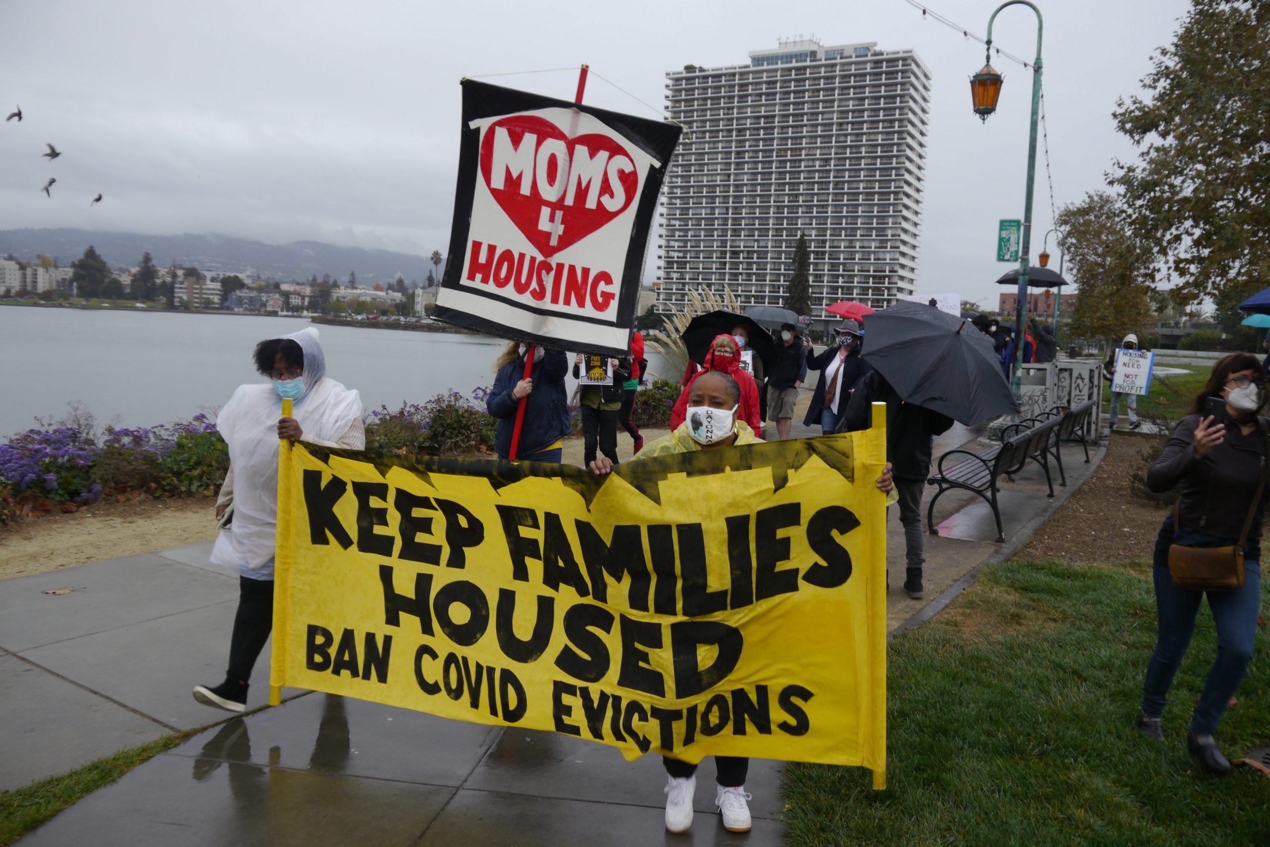 Participants of a Moms 4 Housing rally hold up signs that read "Keep Families Houses" and "Moms 4 Housing."