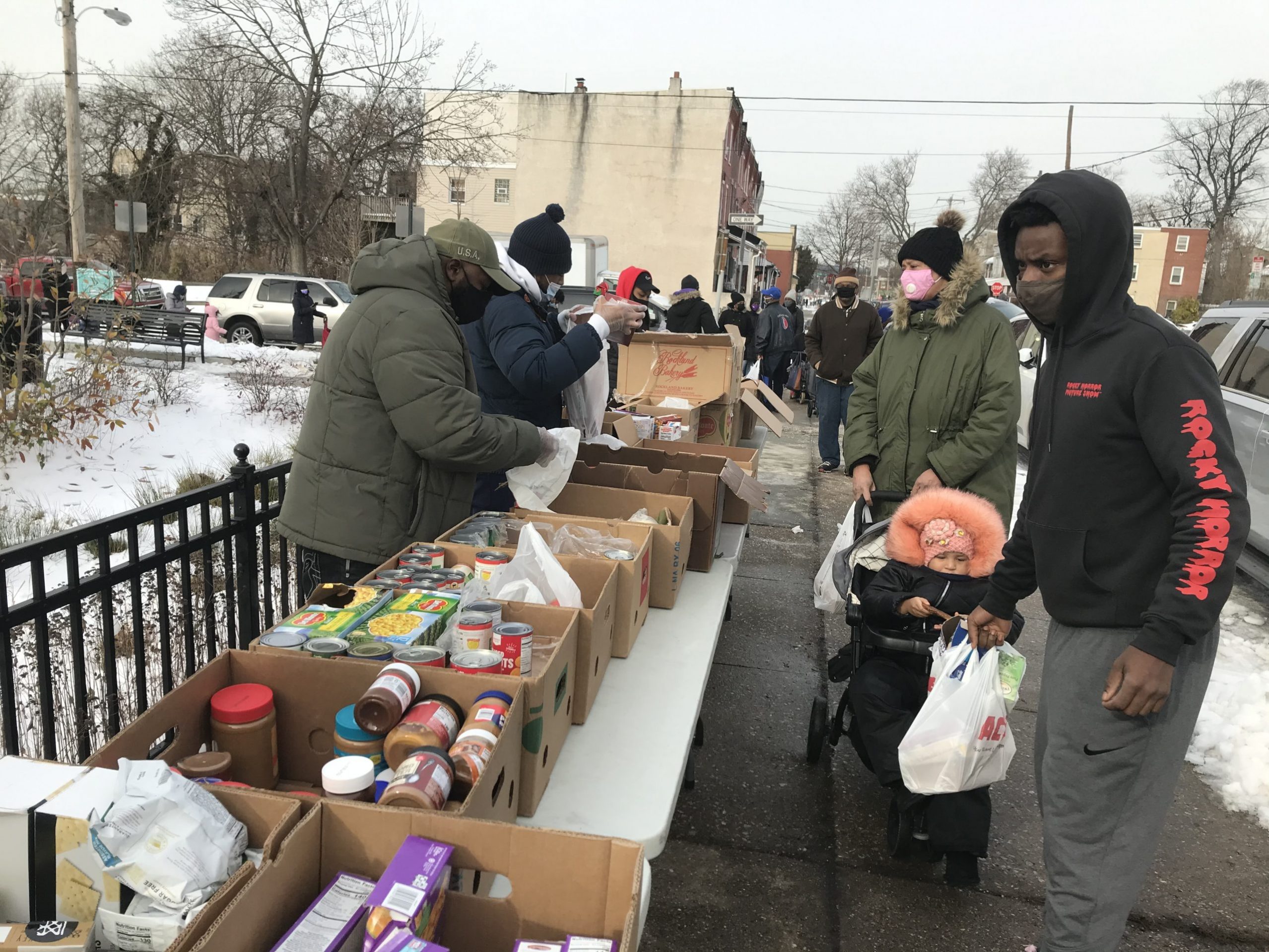 People stand in line to get food distributions on the street in Philadelphia.