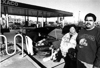 photo of two people standing near a Texaco gas station