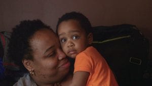 Still photo from The Place that Makes Us, a documentary about Youngstown, Ohio. Image shows a woman holding a small child.