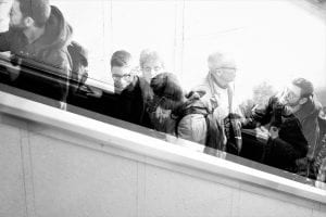 a black and white photo of people on a stairwell, so people are blurry. This image represents cities have led the way in enacting equity-focused pandemic policies. 