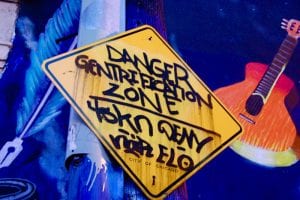 Close-up of a yellow sign hand painted with the words "Danger/Gentrification/Zone"