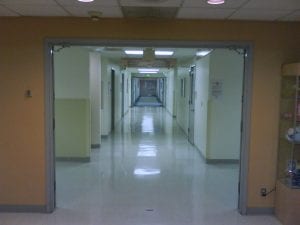 A view down an empty hospital hallway, accompanying an article about rural hospitals and the social determinants of health.