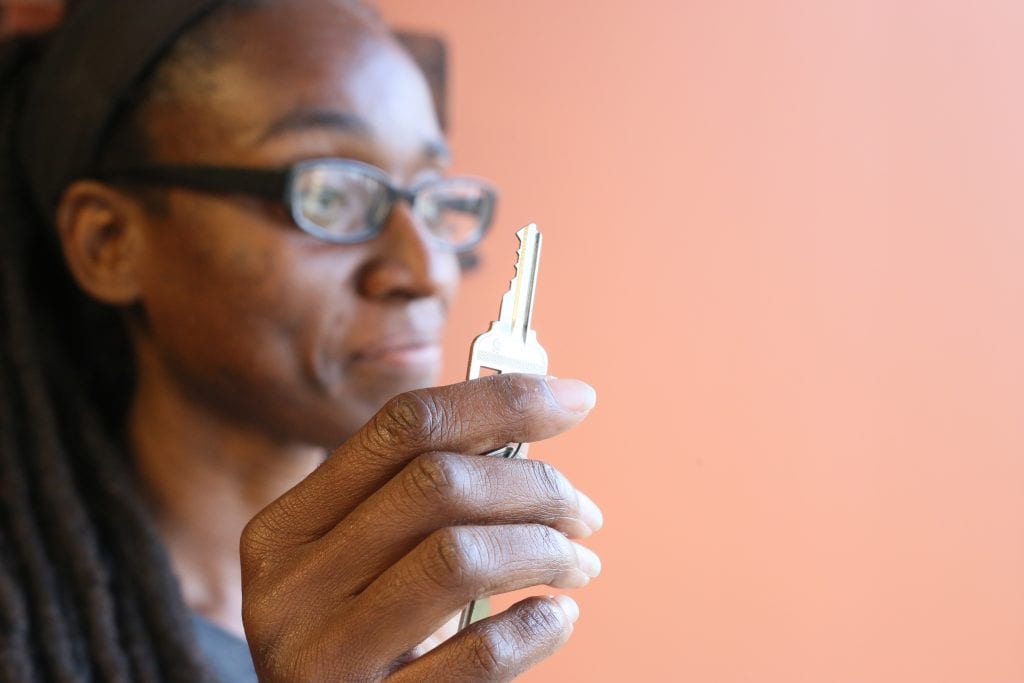 Photo of Makeisha Robey holding a key (in the foreground, in focus) to her new home, purchased through the Atlanta Land Trust.