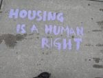 In purple chalk, it says "Housing is a Human Right."