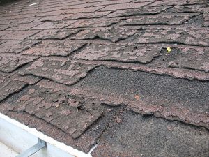 Close-up view of dilapidated asphalt roof shingles, illustrating article about the Biden infrastructure plan and its potential for affordable housing