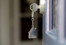 Open door to a new home with key and home shaped keychain.