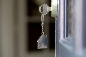 Open door to a new home with key and home shaped keychain.