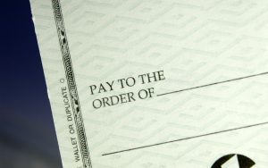 close-up photo of the part of a pale green check that says "pay to the order of" to illustrate an article about databases and other housing tools for tenants