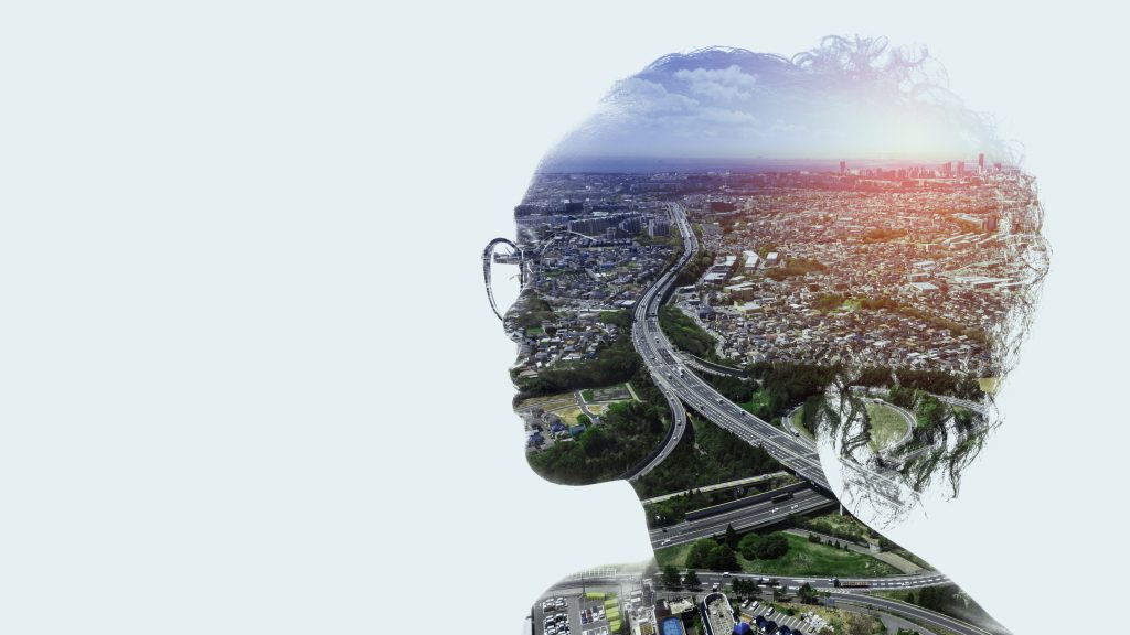 Illustrating solutions to homelessness: Against a plain off-white background, a composite image of a woman's head and shoulders with aerial view of a city visible within the silhouette. She is looking to the left, and the city view shows a highway and crowded neighborhoods. 