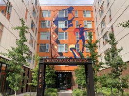 A large affordable housing development with a large mural that includes Black musicians on the front wall.