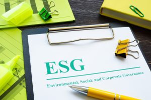 Stock photo showing a desktop with clipboard holding papers about ESG (Environmental, Social and Corporate Governance), criteria used when designating a company a B Corp, a notepad, and other desk supplies.