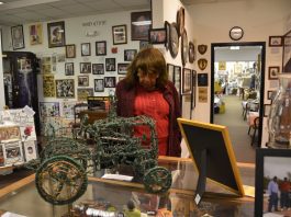 A woman wearing a redish sweater and shirt look at at a piece of history at the Jack Hadley Black History Museum in Thomasville, Georgia. She is surrounding by other artifacts.