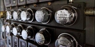 A close-up view of 11 glass-domed electric meters in an apartment building. The photo appears to be black and white at first glance, but is naturally a scene of varying shades of gray.