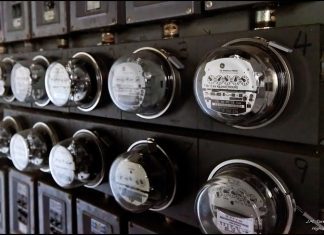 A close-up view of 11 glass-domed electric meters in an apartment building. The photo appears to be black and white at first glance, but is naturally a scene of varying shades of gray.