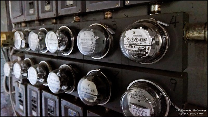 A close-up view of 11 glass-domed electric meters in an apartment building. The photo appears to be black and white at first glance, but is naturally a scene of varying shades of gray.