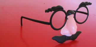 A pair of "Groucho Marx" glasses resting on a raspberry-colored table.