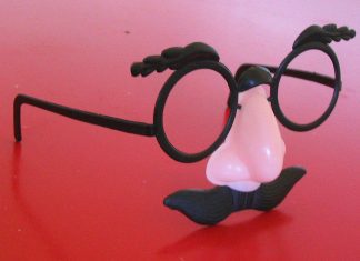 A pair of "Groucho Marx" glasses resting on a raspberry-colored table.