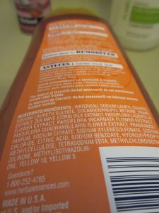 A close view of the lengthy ingredients list on an orange/russet shampoo bottle.