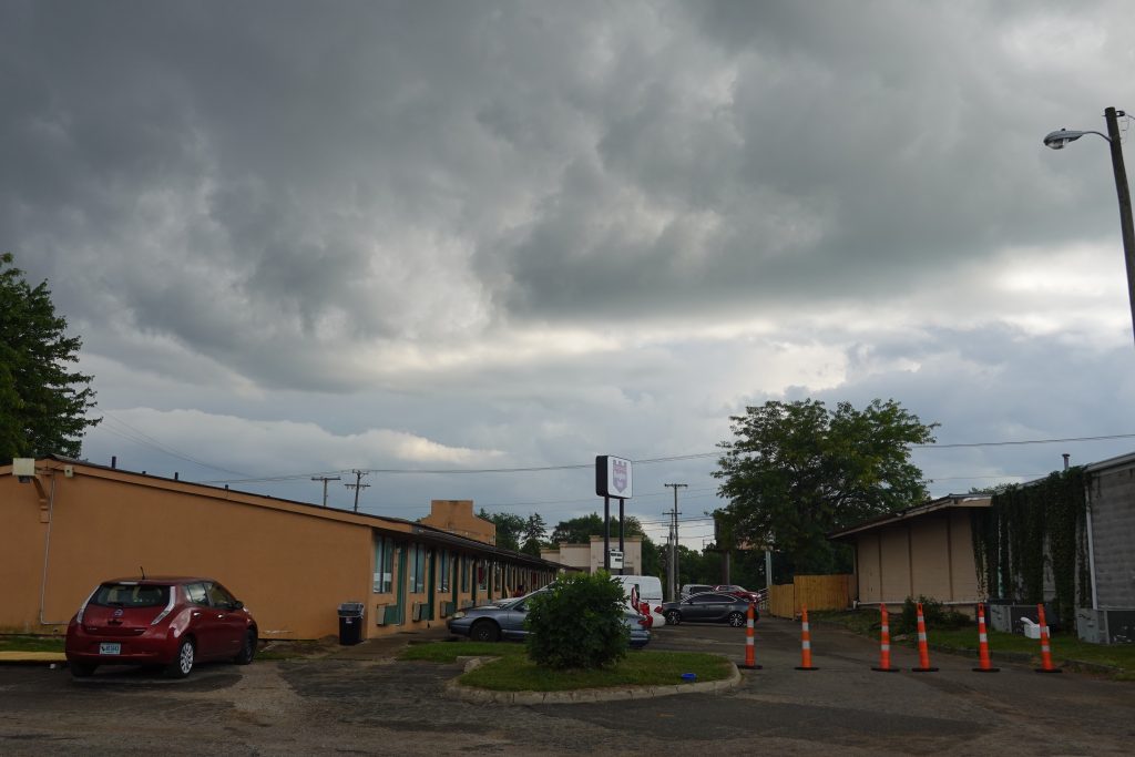 A view from a parking lot of a one-story motel on a cloudy day.
