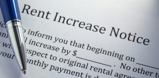 Close-up of document titled "Rent Increase Notice." Text is partly hidden by a blue and silver ballpoint pen. Visible text says "...inform you that beginning on ____ .... increase by $_____. No other ..... to original rental agreement.... monthly payment is due on the first...."