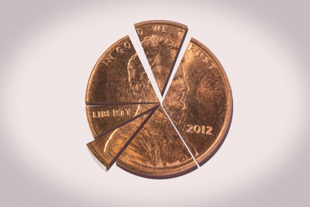 Close-up of a 2012 copper US penny, cut into six pieces of unequal size.