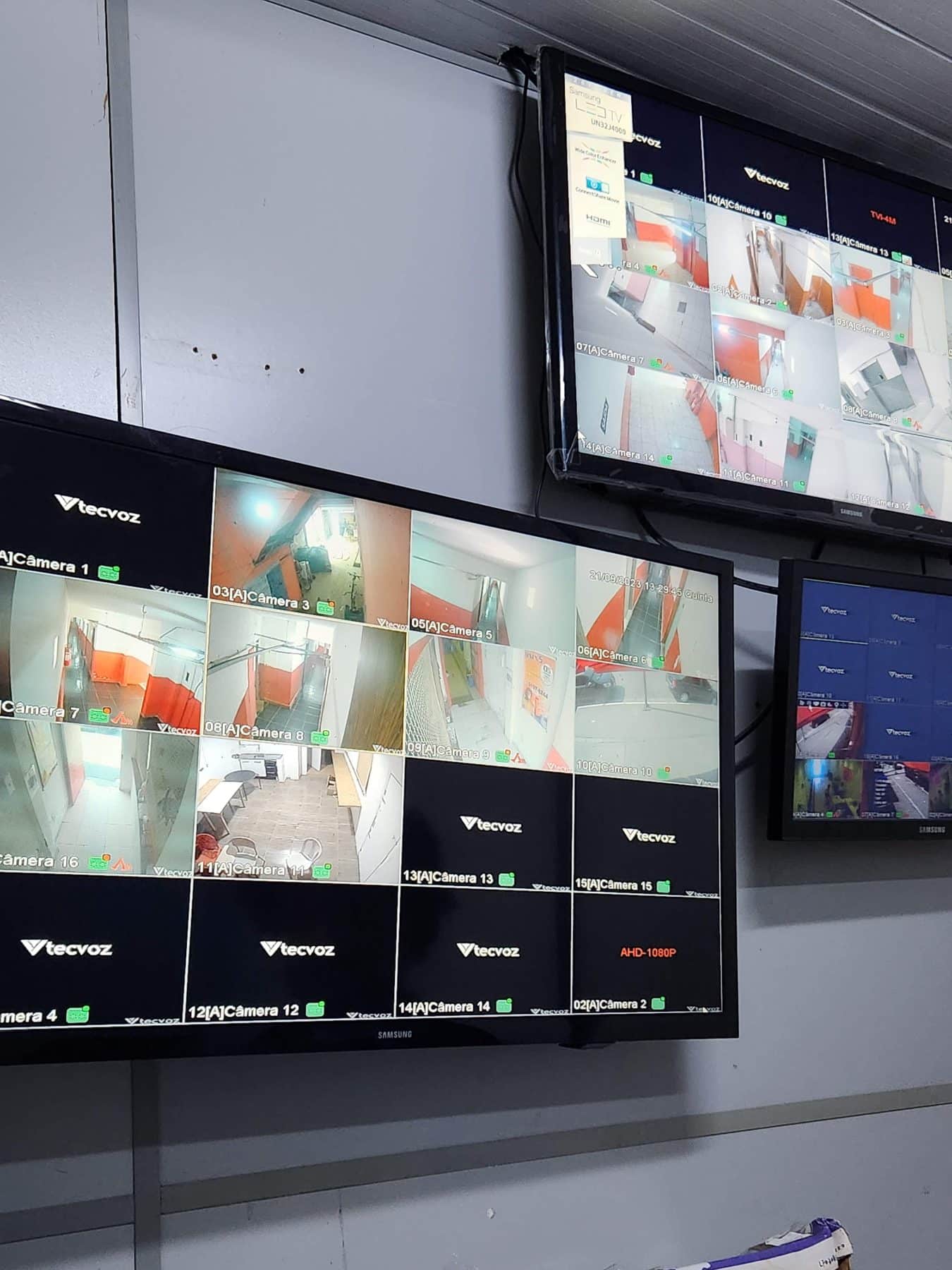 Two screens show multiple security camera views of the interior of a building. Photo by Roshan Abraham