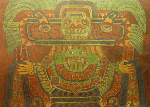 An ancient mural of a female deity, in tones of green and rust/brick, with some blue. Her face is green, her eyes wide open and staring, and her hands held out to the sides. She wears an elaborate headdress made of feathers with a birdlike visage on it.