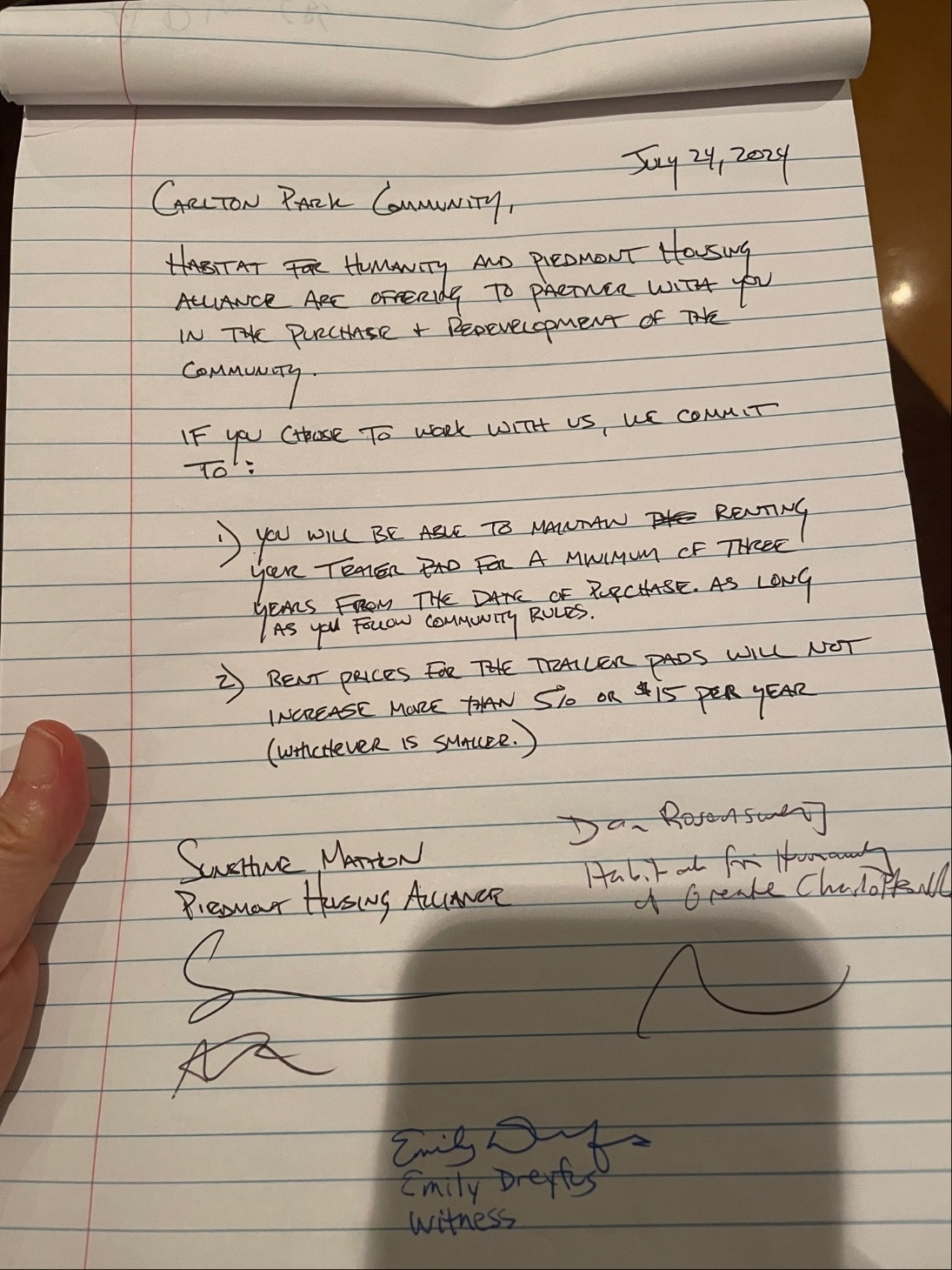 On lined white paper, a document handwritten in block capitals. Dated July 24, 2024. Signed by reps from Piedmont Housing Alliance and Habitat for Humanity, witnessed by Emily Dreyfus