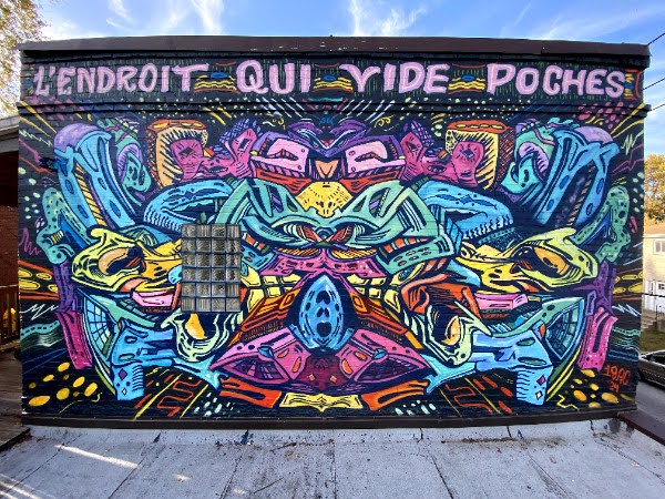 A vibrant multicolored mural on a black wall, in reds, blues, greens, and yellows. At the top, in handpainted letters, it reads "L'Endroit qui Vide Poches"