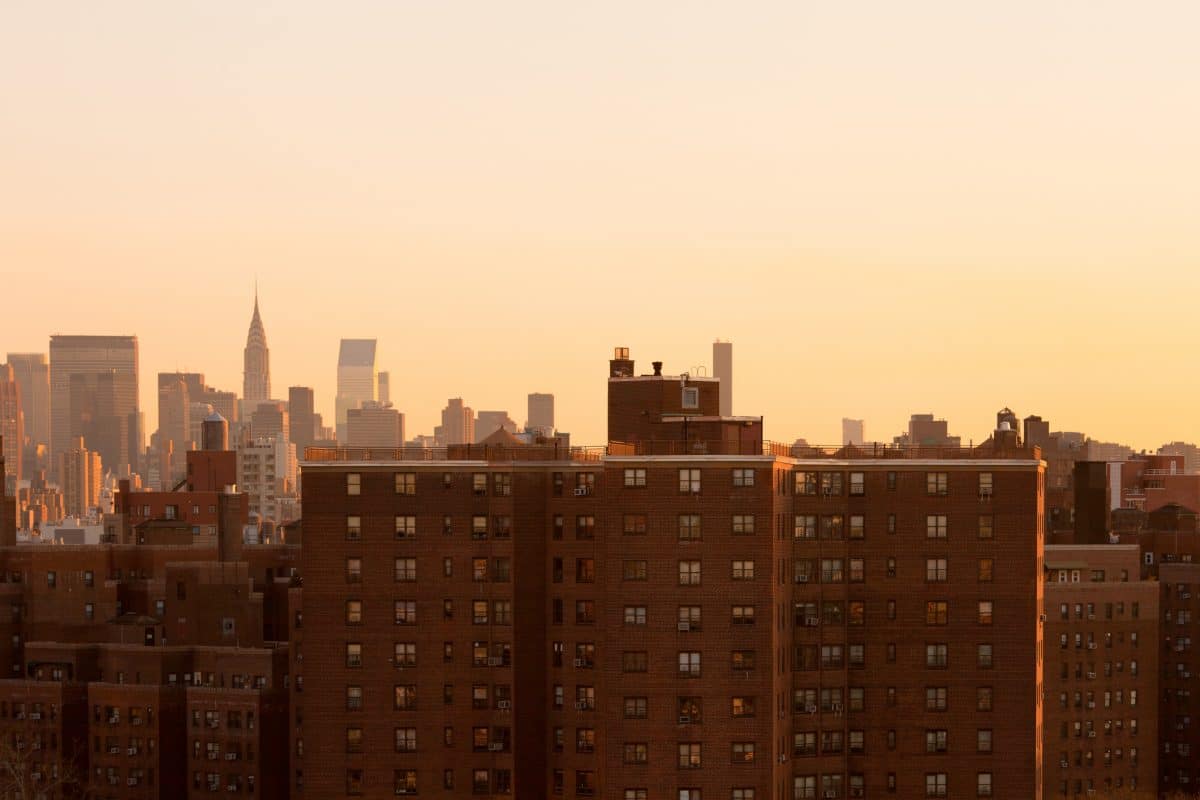 The NYC skyline in golden light, with brick buildings in front.