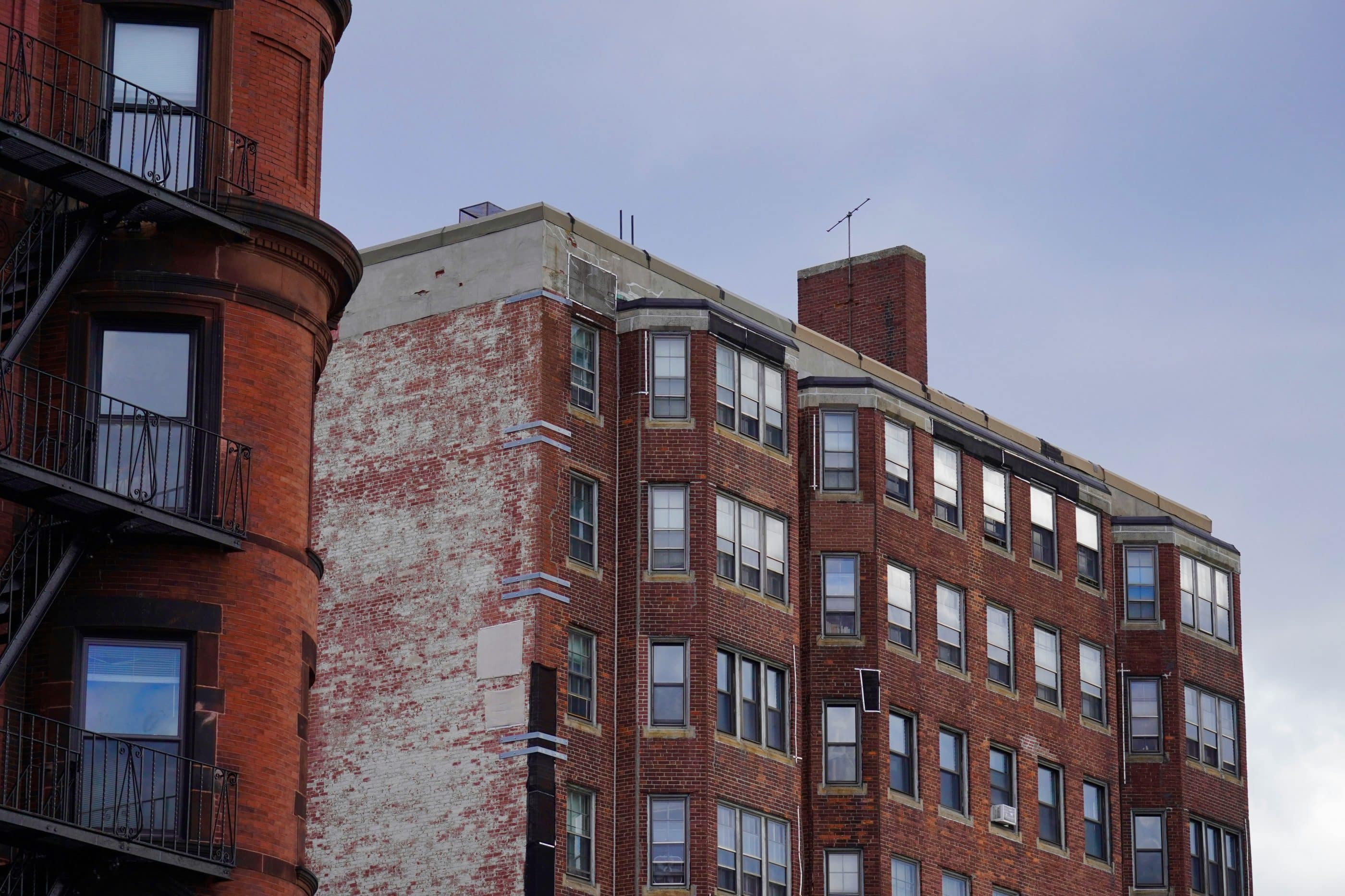A large brick apartment building set against a cloudy sky.