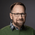 Headshot of a man with brown hair and glasses
