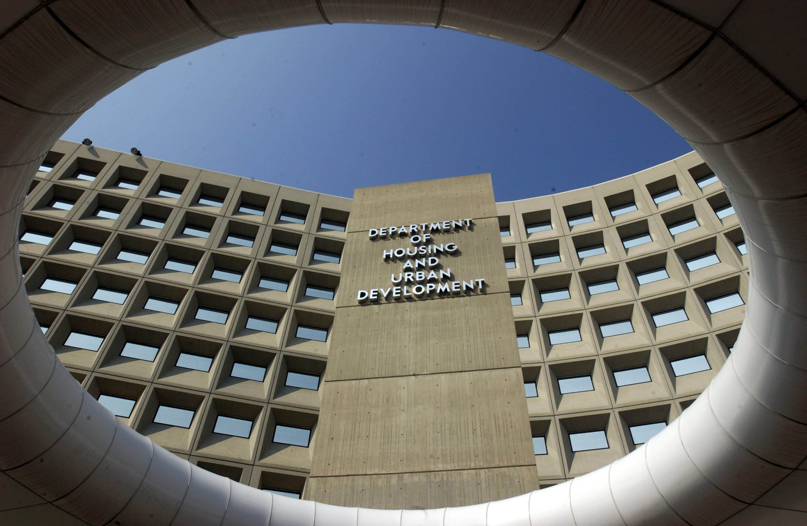 The front of a large concrete building with many exterior windows. Large capital letters on the top of the building read DEPARTMENT OF HOUSING AND URBAN DEVELOPMENT.