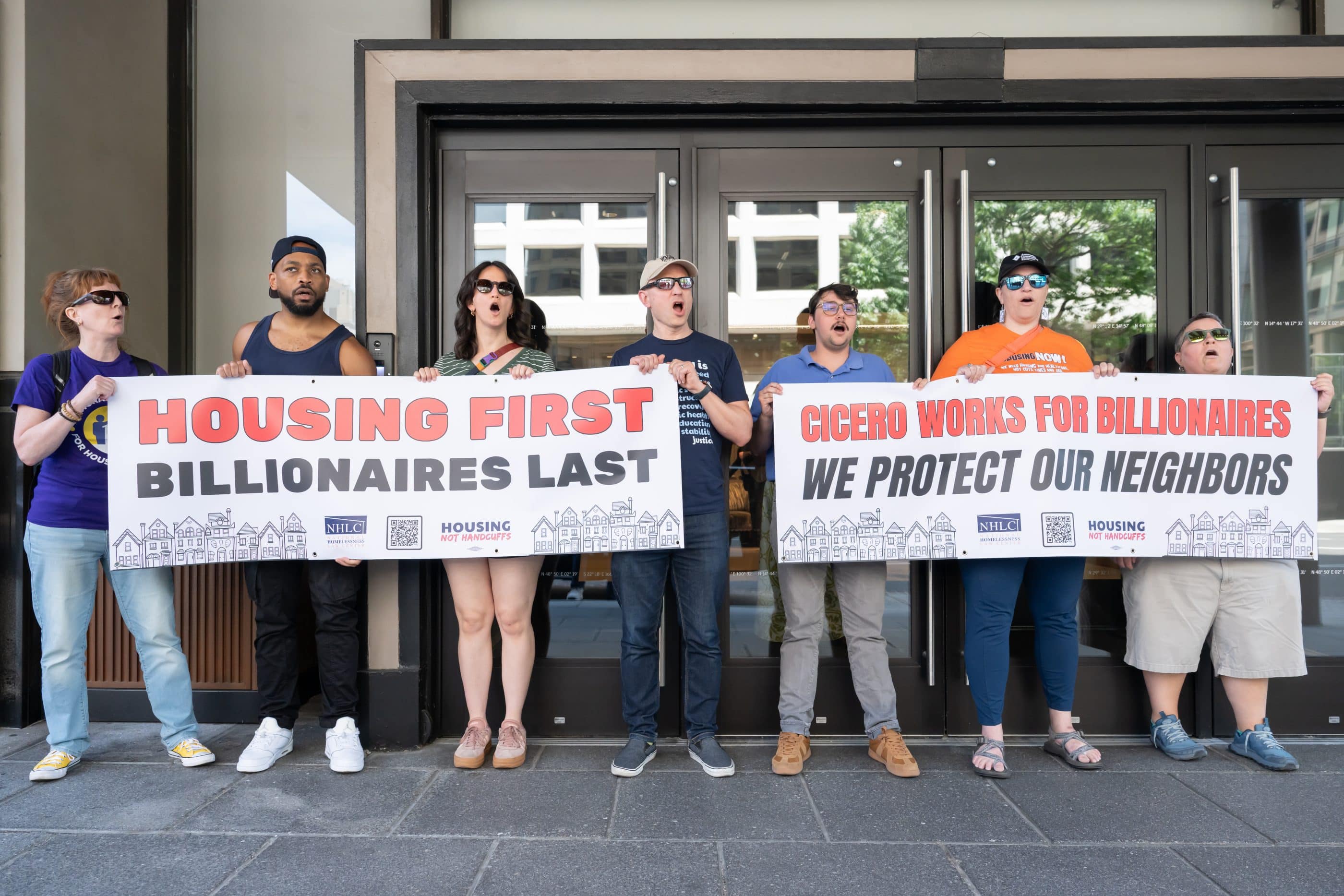 Advocates hold banners that say "Housing first billionaires last" and "Cicero works for billionaires, we protect our neighbors."